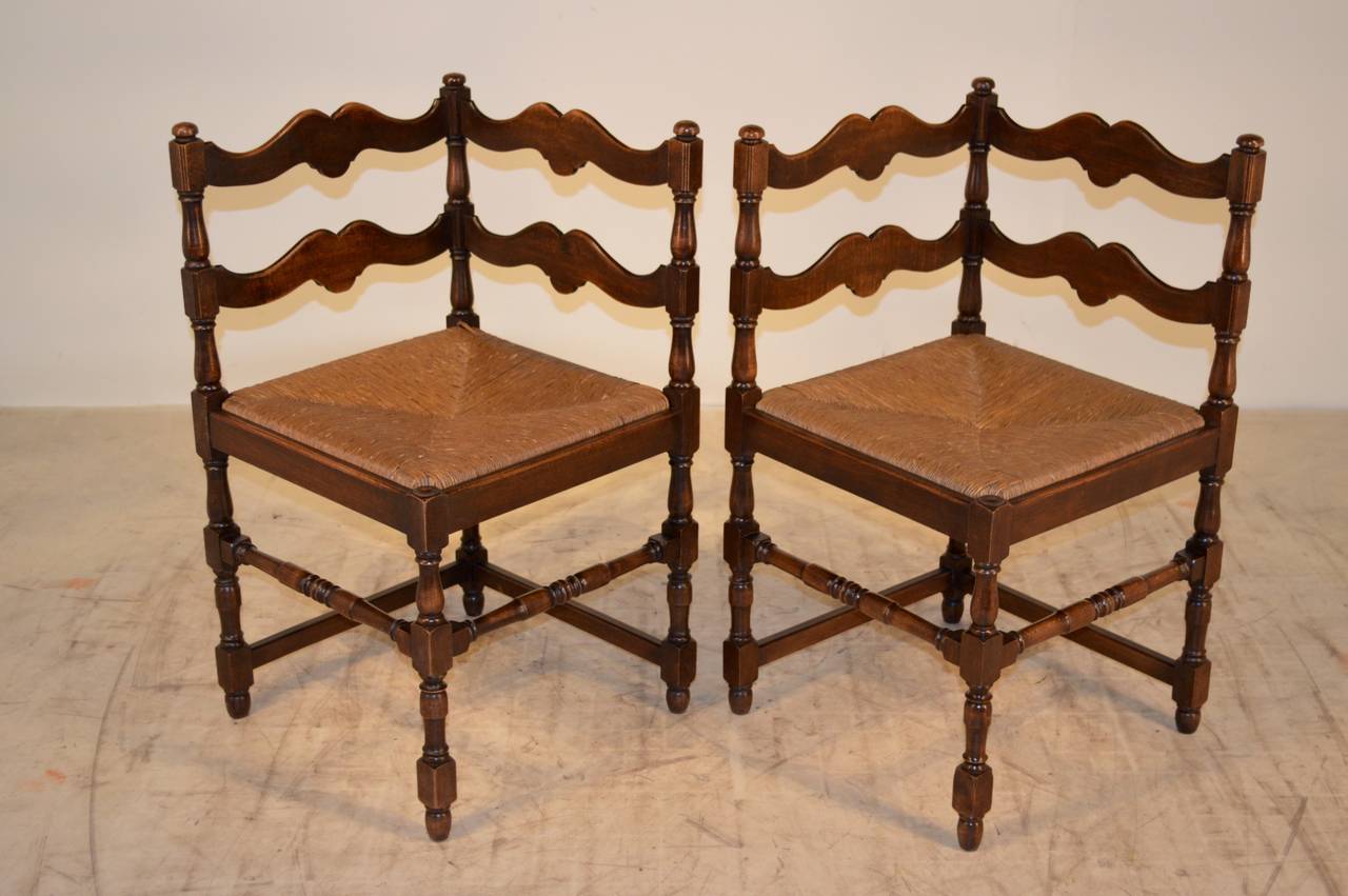 19th century pair of French coroner chairs made from oak.  The backs and sides are made up of scalloped slats and finished at the tops with finials.  The seats are original rush and follow down to hand turned legs and stretchers.  The seat height