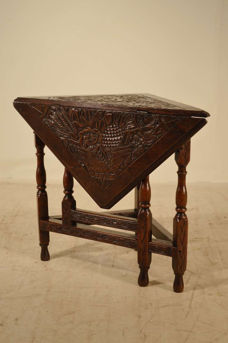 Early 19th-C. English oak handkerchief table with wonderfully beveled edge around the top with gorgeous carved decoration.  The apron is also carved and follows down to wonderfully turned legs, joined by stretchers.  Top open measures 32 x 31.