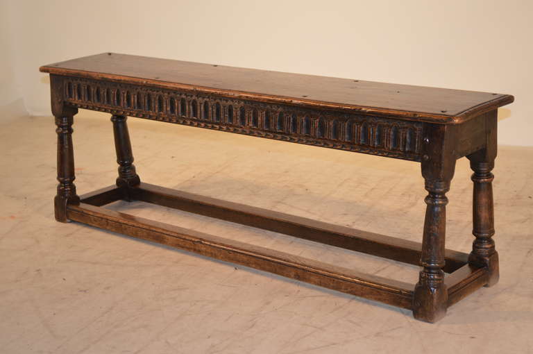 c. 1670-1690 English oak joynt bench with a beveled edge around the plank top, fastened with pegged construction.  The base has a wonderfully decorated apron with fluted decoration on one side and a carved edge on the other side.  The legs are