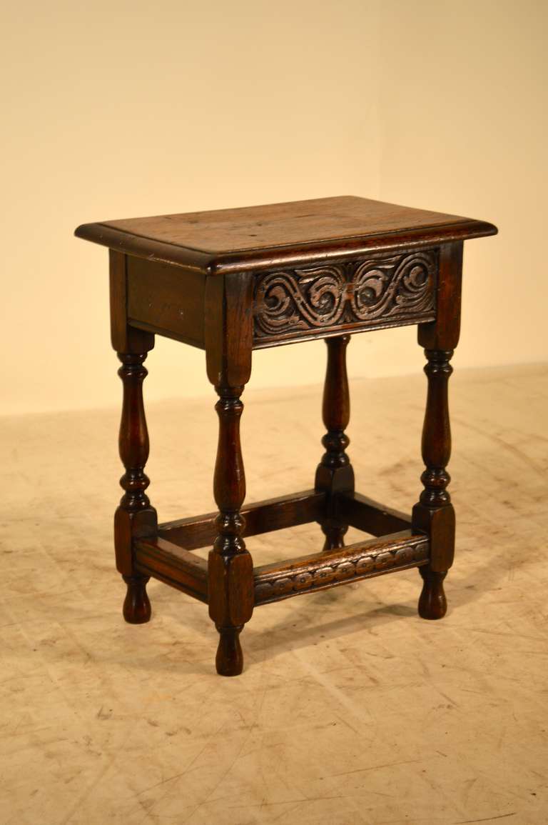 19th-C. English oak joint stool with beveled edge around top following down to a carved decorated apron on the front and back and lovely turned legs which are joined by carved and molded stretchers.  Raised on turned feet.
