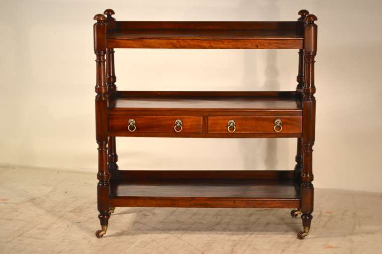 19th-C. English mahogany dumbwaiter with three shelves and two central drawers.  The shelves are wonderfully figured mahogany.  The shelf supports are lovely hand turned and are supported on original casters.