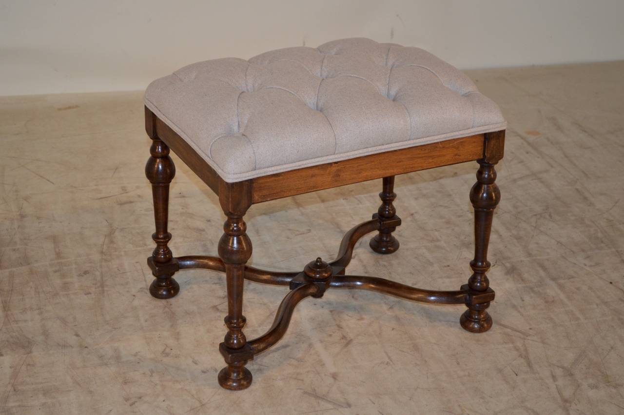 19th Century hand turned walnut stool with wonderfully turned legs, joined by serpentine cross stretchers.  The top is upholstered  in linen with a double welt decoration.  Raised on bun feet.