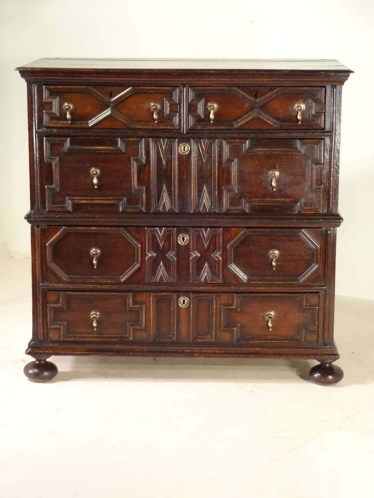 This is a fantastic period geometric two-piece chest.  It retains its original plank top with beveled edge, following down to a two piece case with raised paneled sides and four drawers with geometric molded decorations on each.  Raised on bun feet