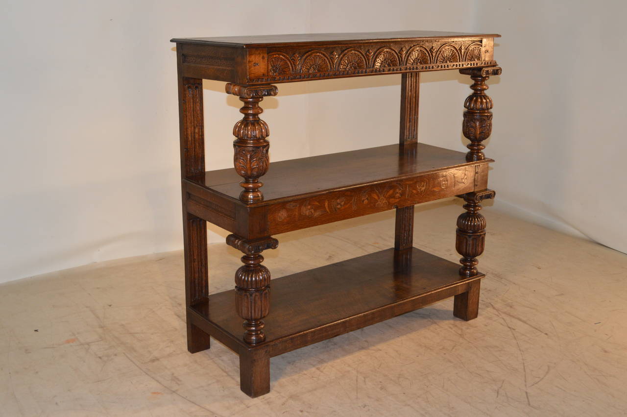 19th Century English oak buffet which is unusual due to the inlaid designs. It has three shelves, which are separated by hand-turned and carved shelf supports in the front and hand-carved flat back supports. This piece has unusual aprons with carved