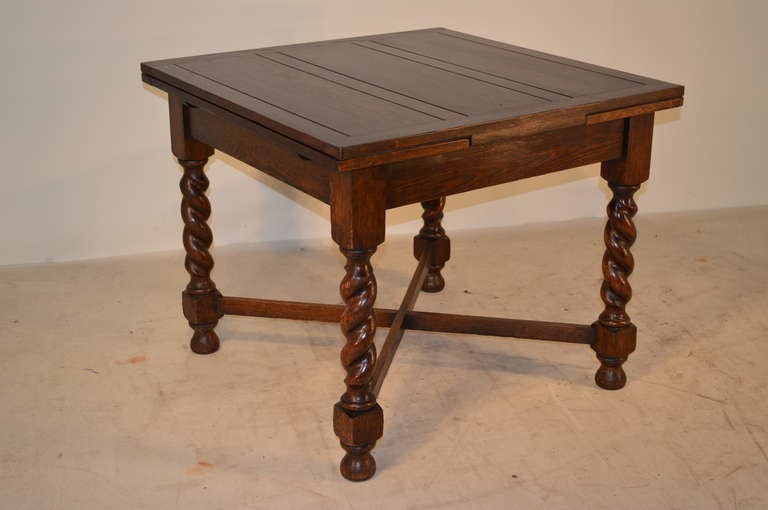 English draw-leaf dining table made from oak, circa 1900. The top and draw leaves are paneled and raised on barley-twist legs joined by cross stretchers. Open top, 60