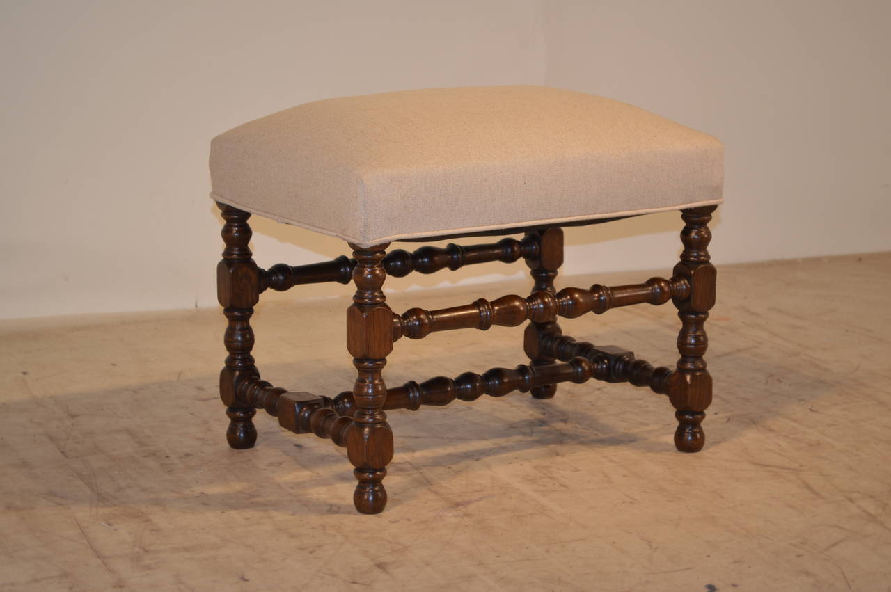19th-C. English oak bench with nicely turned legs and stretchers. Raised on turned feet. Newly upholstered in linen with a single welt decoration.