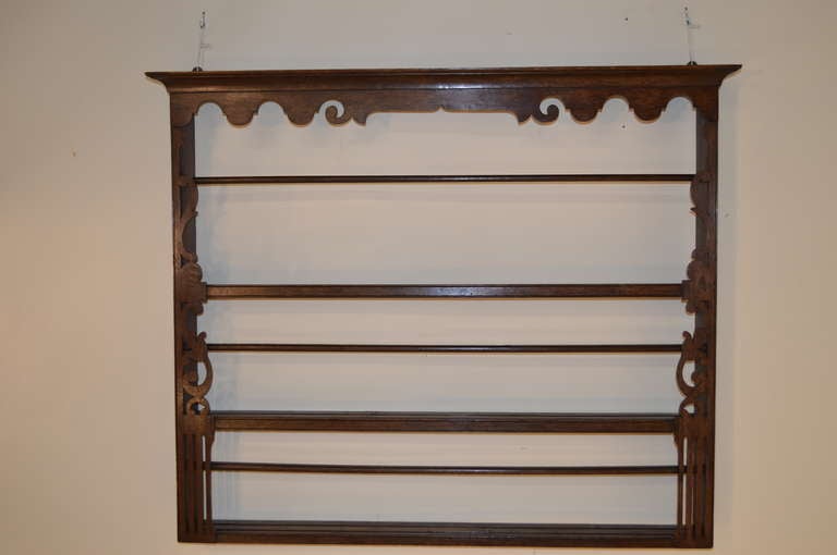 18th-century English oak wall shelf with lovely crown molding at the top, and two shelves with plate rails. The shelf is decorated with pierced and scrolled wooden accents.