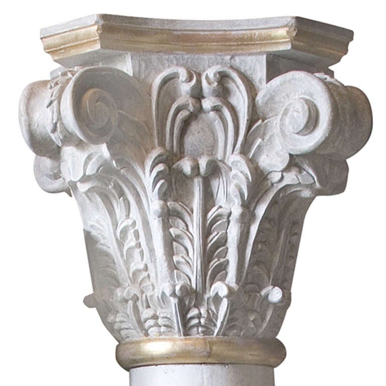 This pair of pillars carved out of pinewood. They are colored in an off-white shade and have gold plated details. In the top the pillars are decorated with acanthus leafs.