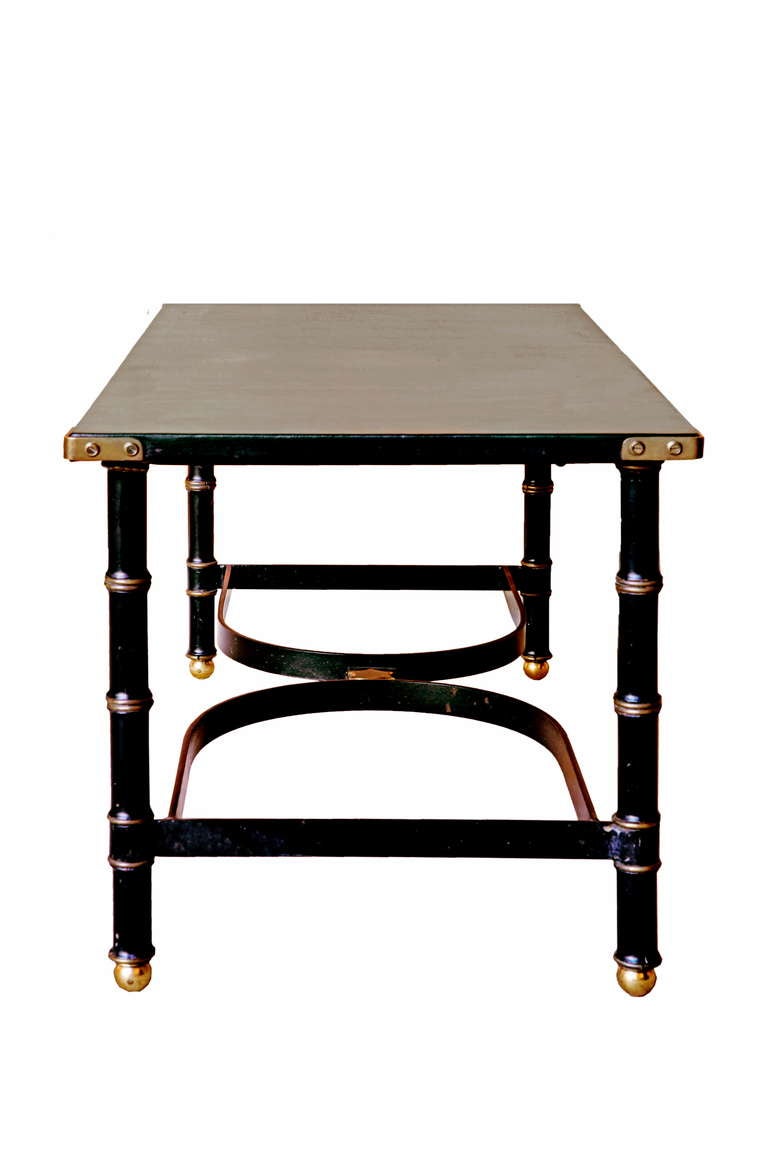 A new black leather top with brass corners on four iron and brass faux bamboo legs. With an 