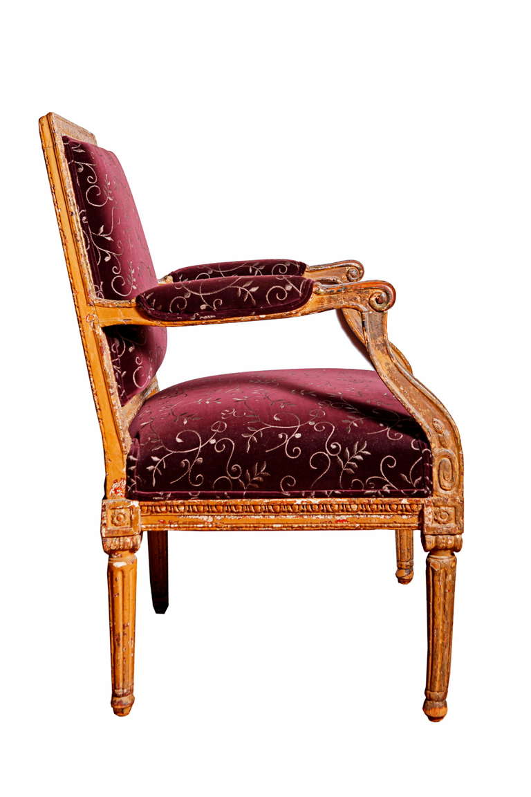 Painted and parcel gilted wood.
Rectangular padded back and seat with armrests on shaped structs, on tapering fluted legs.
Newly upholstered in a bourbon velvet.