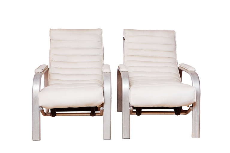 Pair of aluminium articulated lounge chairs with padded white cotton upholstery.