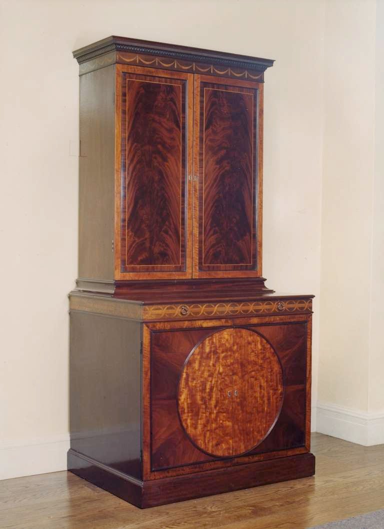 An important George III period mahogany and satinwood cabinet designed by John Linnell. The upper part with a frieze inlaid with classical swags and tails, the doors framed in satinwood, enclose 24 lettered and numbered compartments, the lower doors