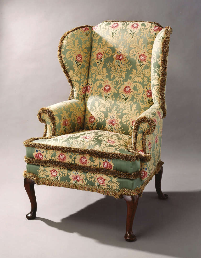 A George II period mahogany and beech framed wing chair with cabriole legs front and back. 
Now covered in a stunning green, red and gold silk floral pattern fabric.