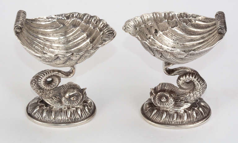 C. 1920s. Un travail magnifiquement détaillé.  Paire de dauphins en métal argenté soutenant une salière en coquillages.  Marque de hall anglais.