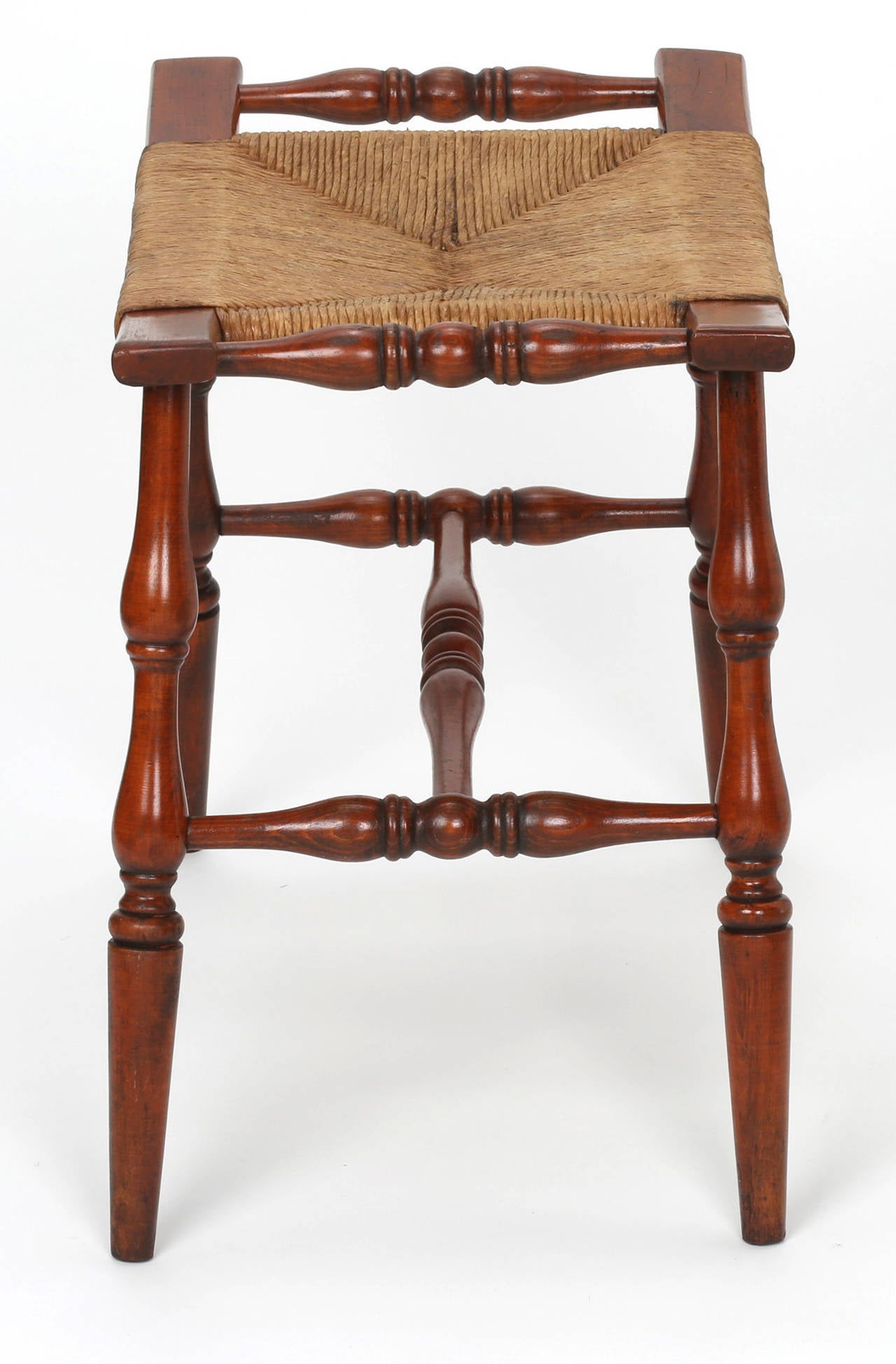 Small bowed rush seat bench.  Sturdy turned legs with turned stretcher.
Charming and comfortable