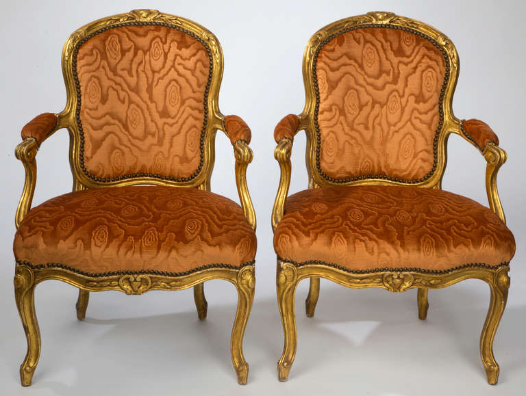 Gorgeous pair of Louis XV Style French arm chairs from late 1800s.
Original gilding on beautifully carved wood frame.  Newly upholstered in silk moire cut velvet.  Dramatic coloration of rust orange and gold.