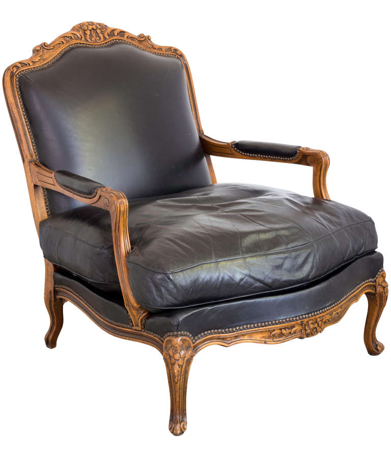 Sumptuous and comfortable deep (27") lounge arm chair.  Down filled cushion.  Beautifully carved walnut, Louis XV style frame,upholstered in soft black leather, aged nicely.