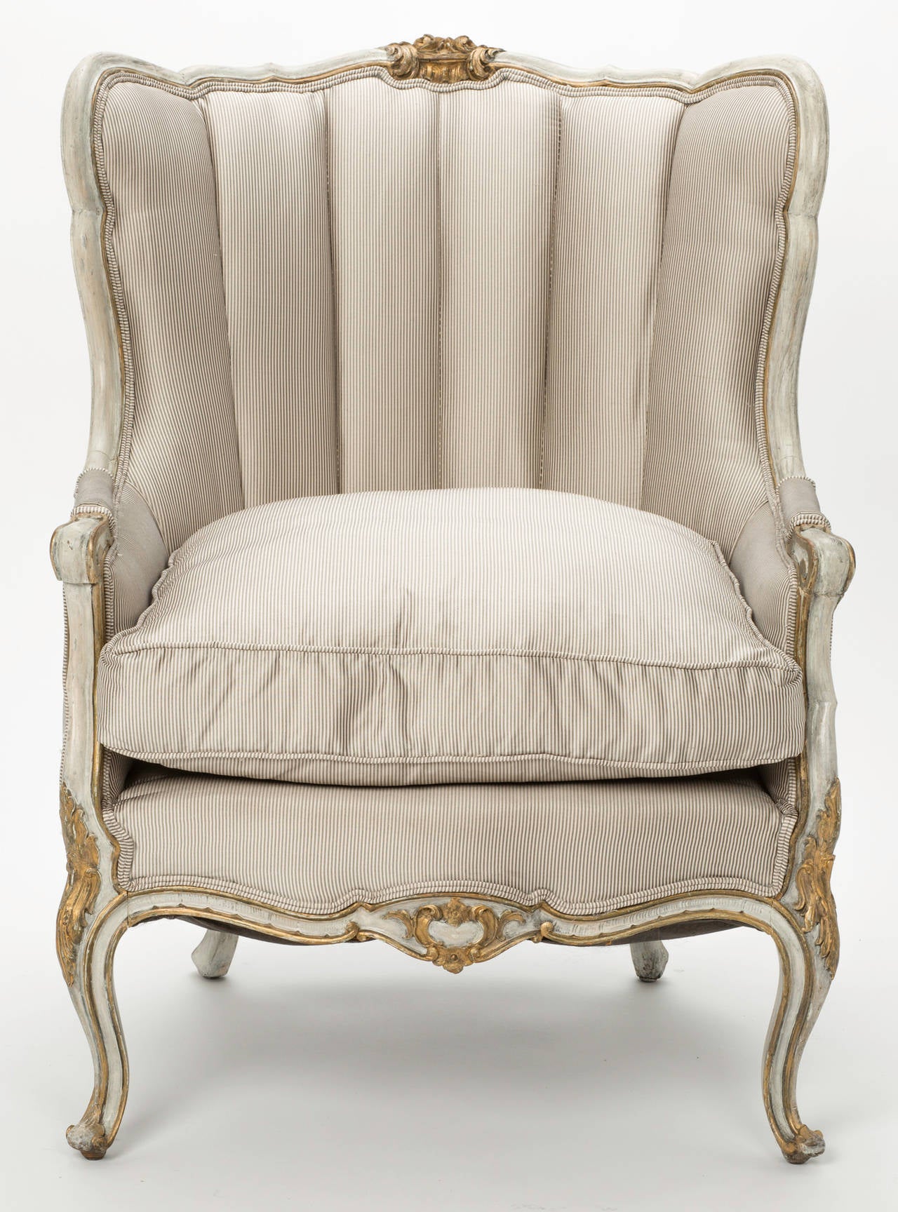 Lovely and comfortable French wingback armchair. Carved painted hard wood frame with gilt accents. Newly upholstered in pewter and cream silk taffeta pin stripe, circa, 1880s. Soft channel back and down seat cushion. Amply sized for comfort.