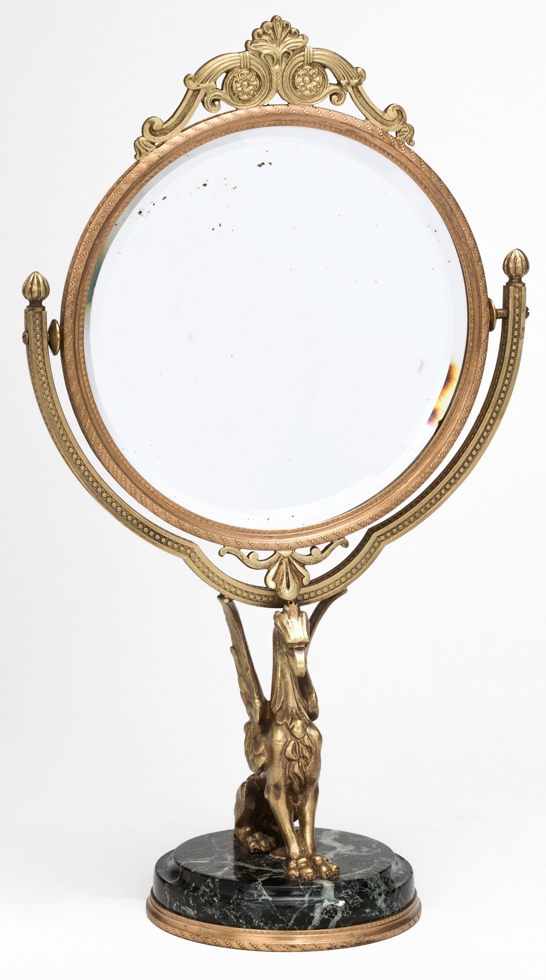 Circa 1930s. Rare decorative vanity tilting table mirror. Gilt bronze frame with bevel mirror, supported by gilt bronze griffin on round marble base.