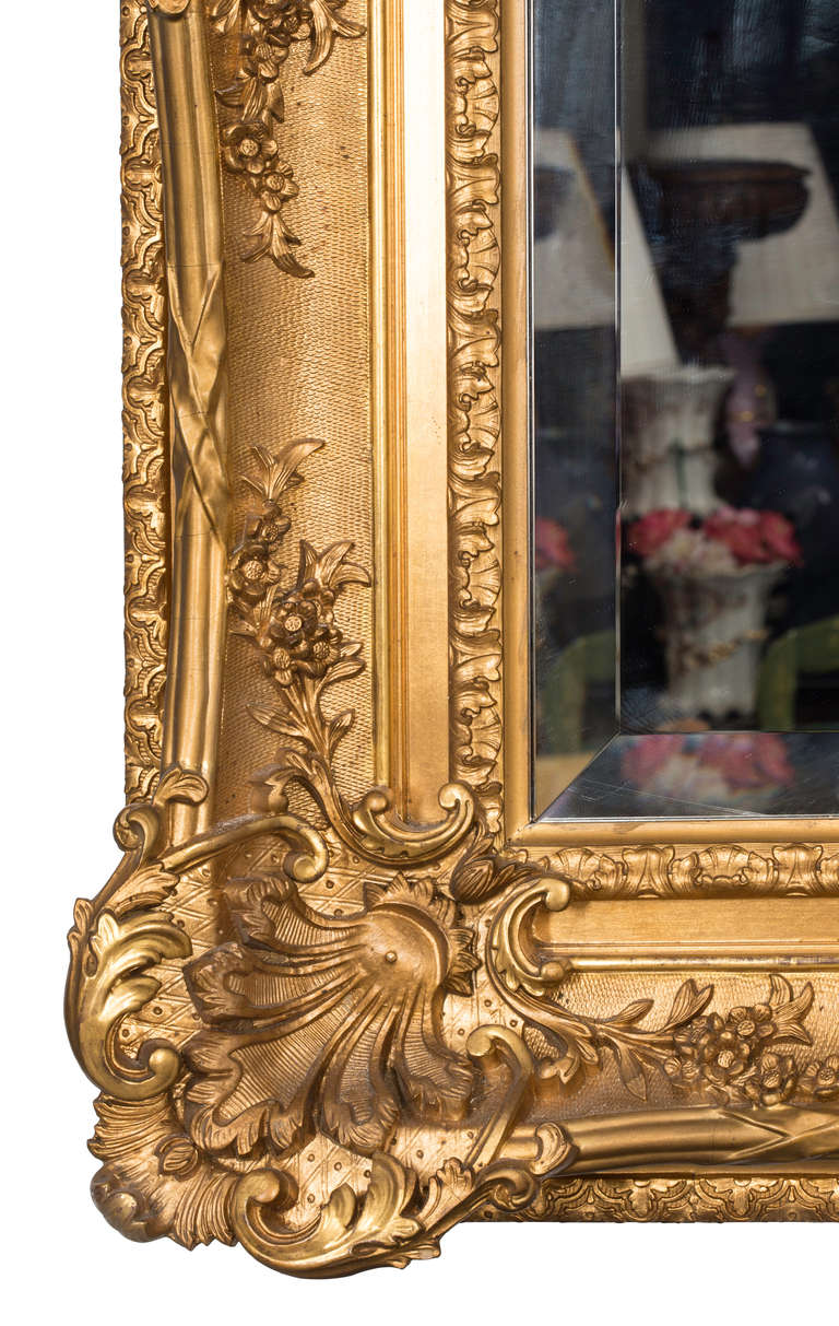 Beautifully detailed carved  late 1890s mirror in 24k water gilt.  Newer beveled mirror.