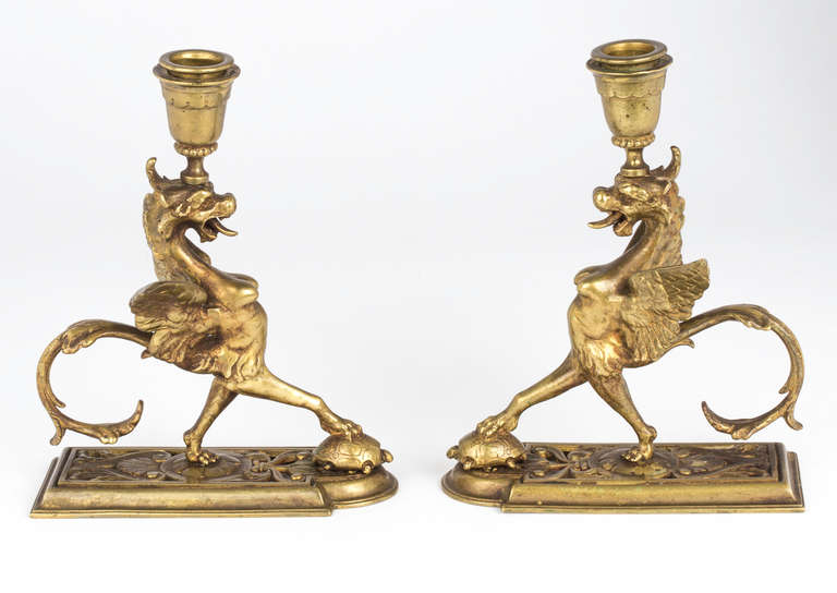 Exceptional pair of antique brass candleholders of griffin holding a turtle. Griffin symbolizing power and faithfulness, turtle for longevity.