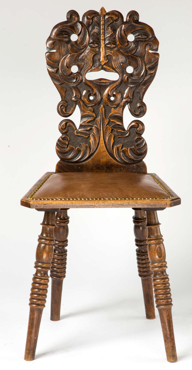 Charming and whimsical, beautifully carved  walnut hall chairs.  Seat is newly recovered in leather similar to the original leather.   It is finished with brass nail studs.   All four legs are turned. 
English C.1890s. .