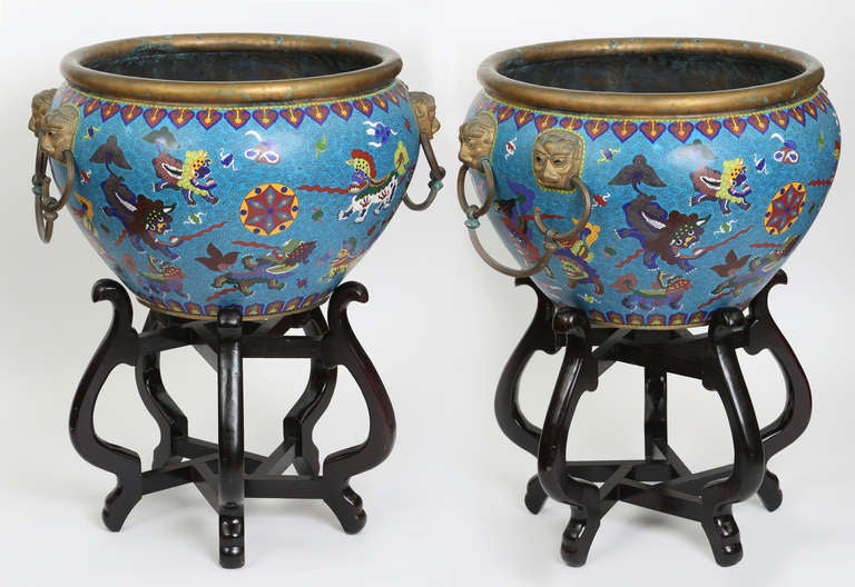 Fantastic coloration on these very large jardinieres with wood stands.
1930s,  China, wonderful cloisonné  enamel work.
Each sides are double lion faces with brass handles.
These will dramatize any entry way.  
Wood stand 18 high x 24
