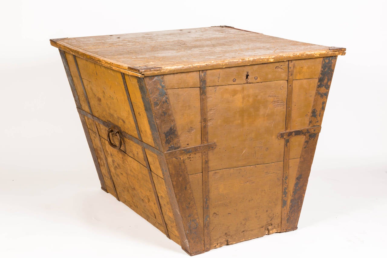 Large wooden box with iron metal straps. Hinged wooden lid. Made to use on ship for storage. Wider at the top as it narrows down to 24