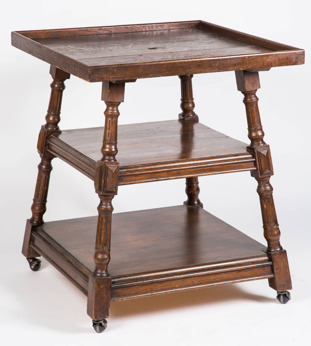 Square tray style table. Three-tiered with wheels. Dark oak wood.