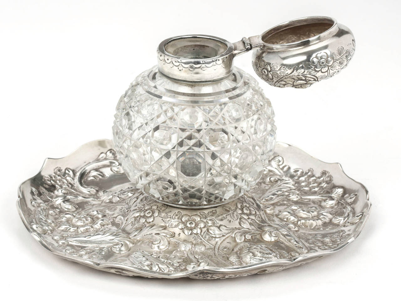 Beautiful English Hall marked sterling and cut crystal ink well.
Cut crystal bottle with sterling lid sits on a exquisitely chased round silver base.
The ink well in the center is not movable.