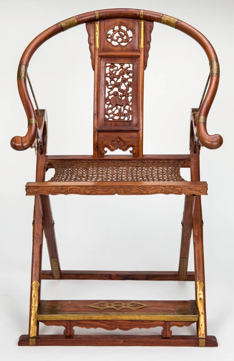 Better in life, Wonderfully sculptural and handsome pair of Chinese folding chairs.  Carved rosewood and woven seats.  Decoratively intricate carved back slat and carved arm support.  Foot rest for comfort.  Easily folds for traveling or storage.