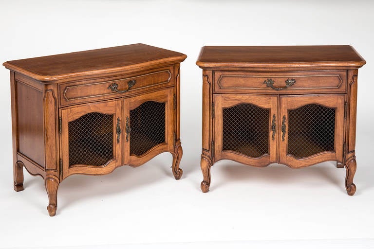 Vintage 1970s pair of bedside tables.  Drawer with cabinet storage below with brass wire doors.  Charming country French style with cabriole legs and carved snail feet.  Beautiful light walnut finish.  Very well made practical pair.