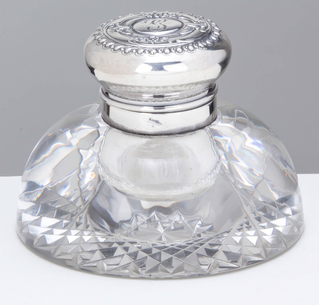 Round crystal ink bottle with sterling hinged lid. Nice monogram on the lid.  Hallmark on the neck.  It is 3.5