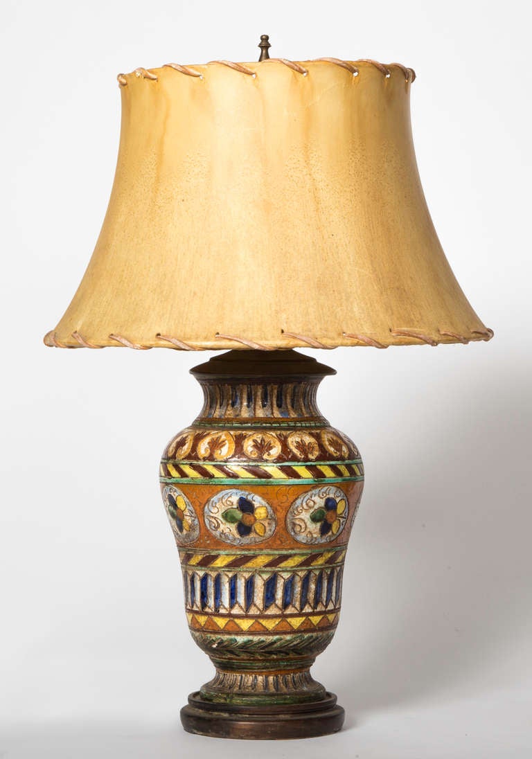 Wonderful coloring of bright warm tones that has been aged over the years.  C. 1930s Mexican pot turned into lamp.  Hand made shade in aged hide with stitched edges.  Two light pull chains.  Wonderful warm light.
Lamp base alone 12h x 7