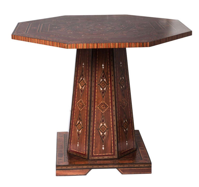 Vintage 1960s.  Octagon shape table top is  Intricately inlaid marquetry work with various specimen wood and shells.  The inlaid work continues to the six sided pedestal and down to the platform.