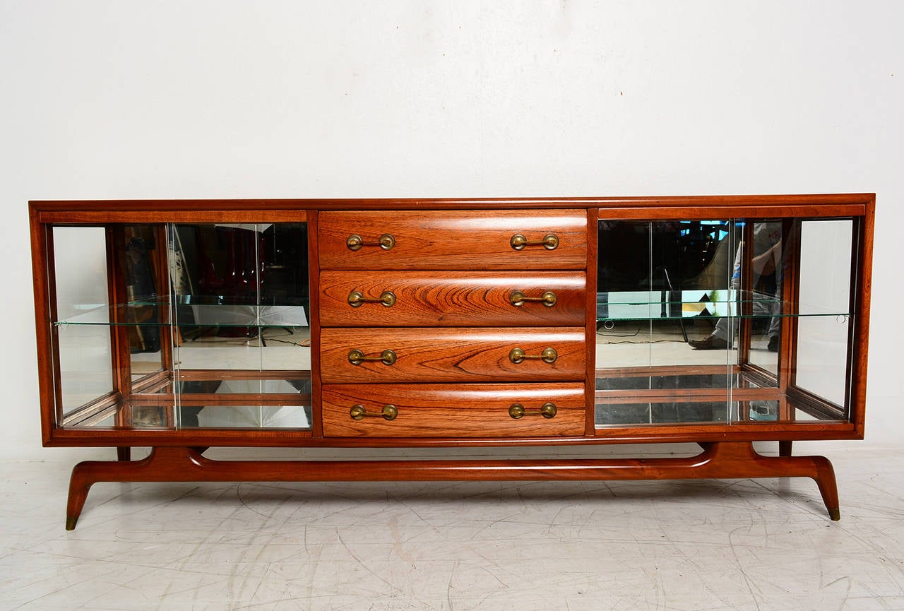 For your consideration a custom built credenza in mahogany wood. Open storage area has glass shelves with sliding doors in glass and back mirror. 

All drawers are constructed with double dove tail joints. 
Solid brass hardware.