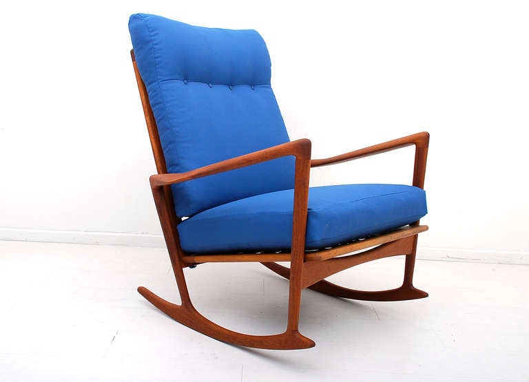 Fantastic sculptural shape. Constructed in solid teak wood. Large spindle back with sculptural armrest and legs. Retains original label from the maker underneath the cushion. New upholstery in blue color. New webbing. 