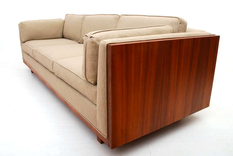 This mid-century modern sofa features a frame in walnut wood on both sides and the bottom as an accent. The back is covered with the same upholstery as the cushions. Solid walnut legs. There is no label from the maker. Attributed in style to Milo