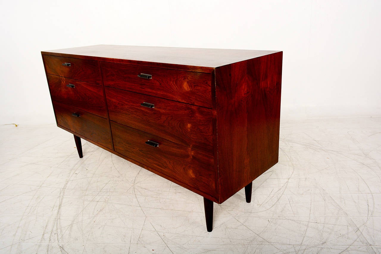 For your consideration a double dresser in exotic rosewood veneer. Peg legs are solid rosewood. 

Sculptural pull-out handles in metal (painted in black).

Unmarked, no info on the maker.