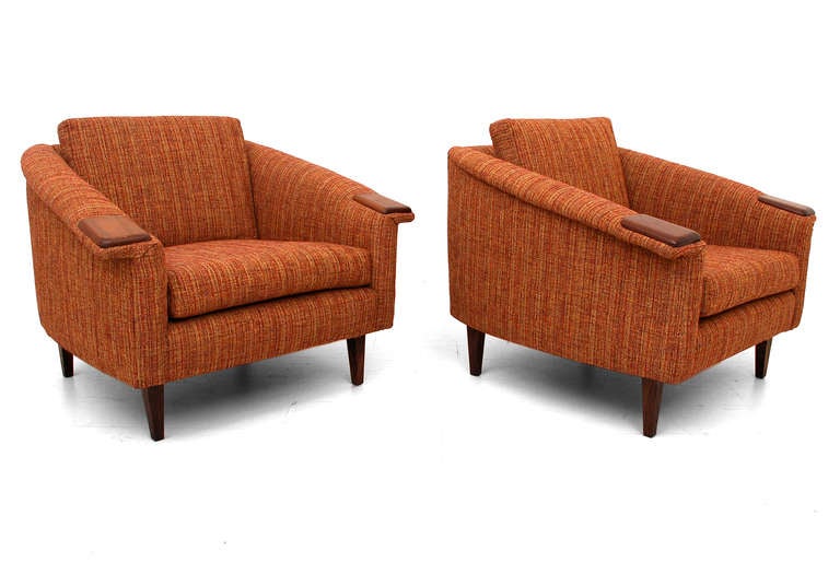 Pair of Mid-Century Modern club chairs. Walnut accent in the arm rest and solid walnut legs. New upholstery. Dominant color is orange tones.