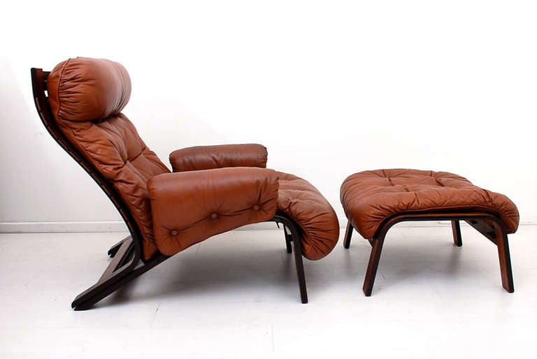 For your consideration a vintage lounge chair with matching ottoman. Bent plywood with rosewood veneer and leather cushions. Leather has vintage wear. Low profile chair with very sculptural shape. Unmarked, no information on the maker or designer.