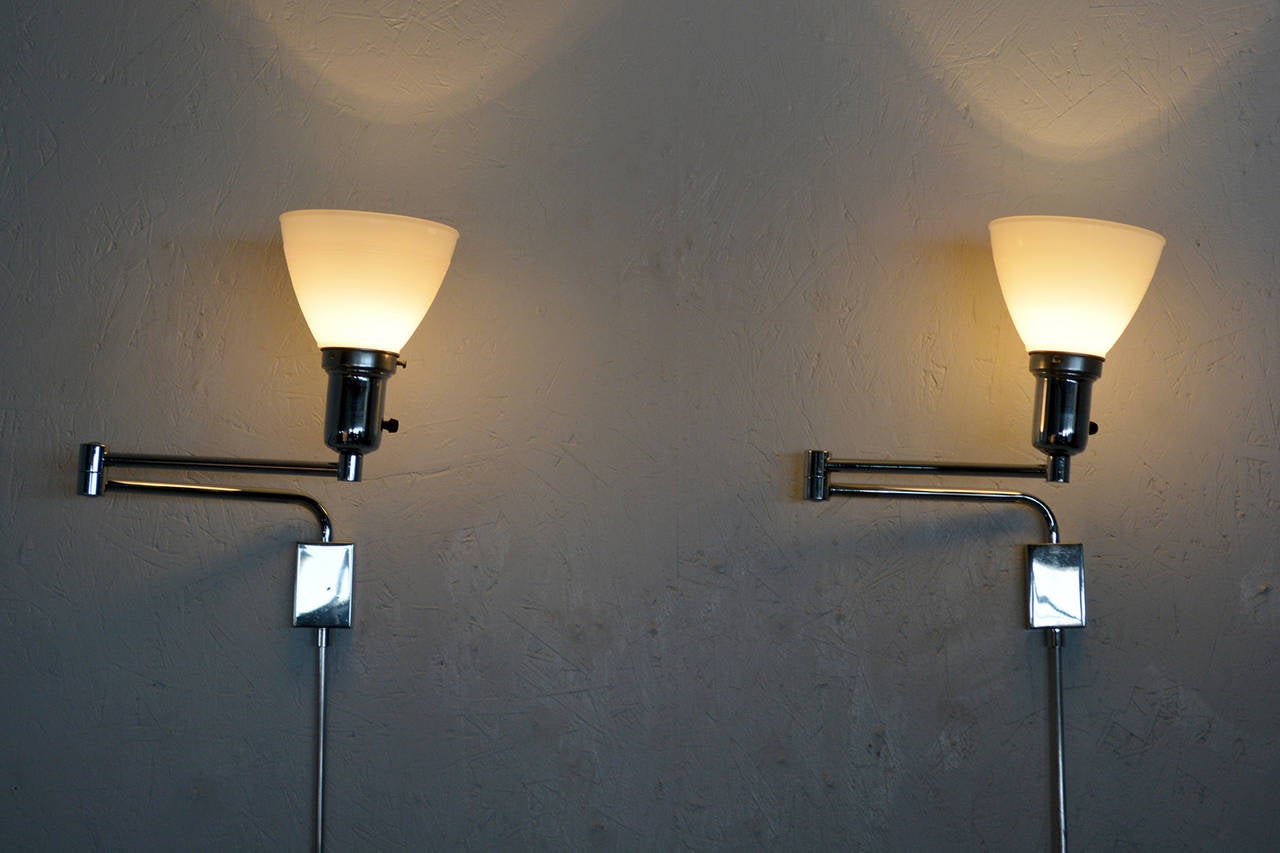 For your consideration a pair of Mid-Century Modern wall sconces. 

Chrome-plated body with milk glass shades. 

Shades shown are for prop only. Sale is for the sconces with glass shades.