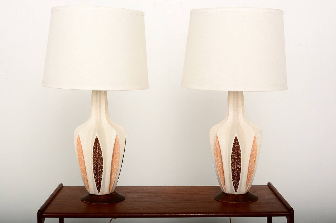 For your consideration a pair of Mid-Century Modern ceramic table lamps with sculptural shape mounted in solid walnut base.

Rewired and ready to go. Shade not included. For props only. 
Stamped in the lower section with the makers information.