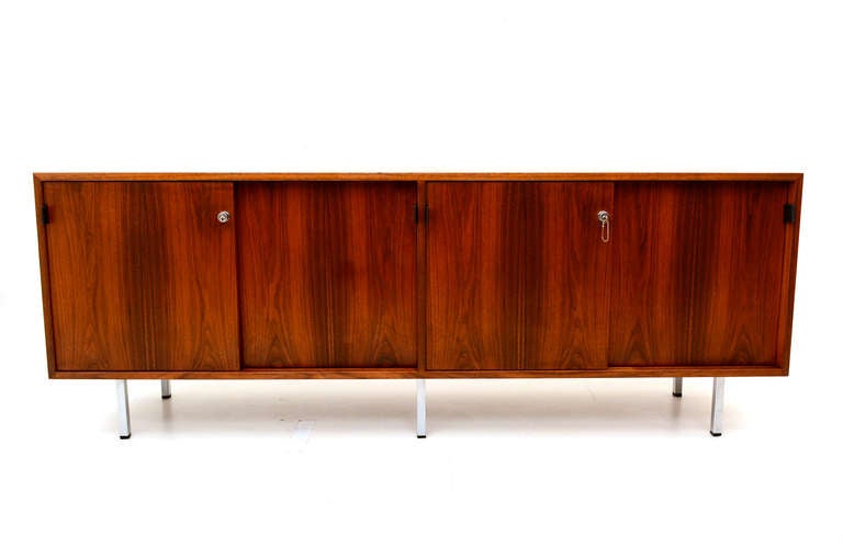 Vintage mid-century credenza designed by Florence Knoll for KNOLL.

Walnut with chrome plated legs and black leather handles. 
Doors have a lock with original key. 

Excellent vintage condition. 