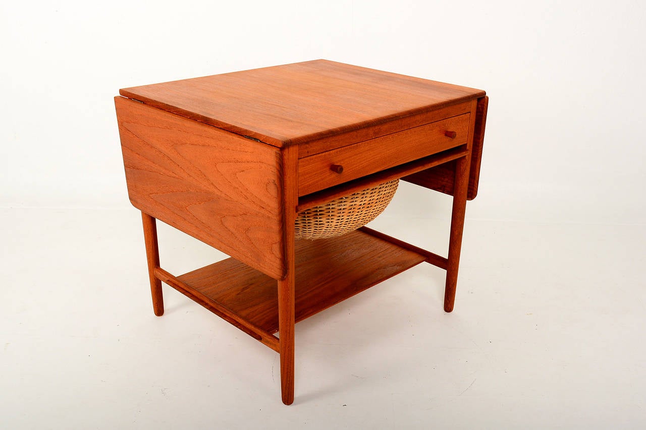 For your consideration a Hans J Wegner Sewing basket.

Solid teak wood with weaved cane basket. 

Table features a pull put basket and a pull out drawer. Built in lower shelf and two drop leaves.

Stamped with makers info underneath the