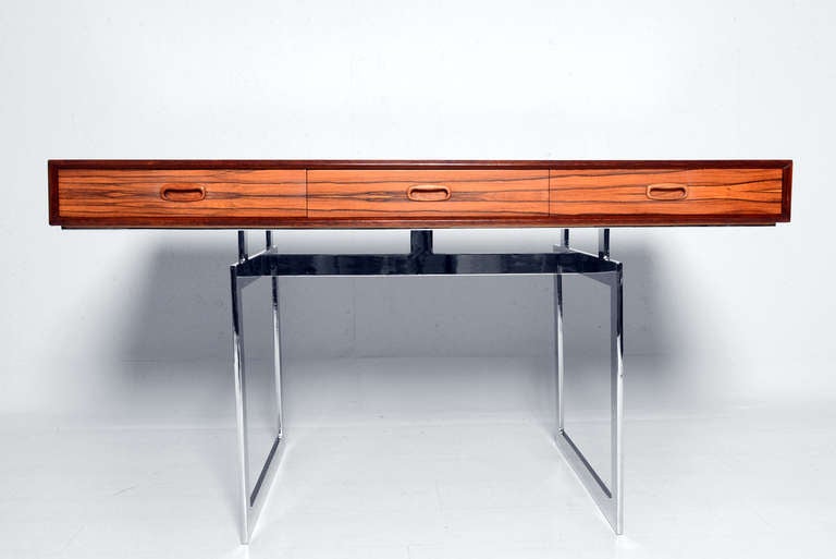 For your consideration a vintage rosewood desk with chrome plated steel base. 

Features three pull out drawers with sculptural pull handle. 

Base is solid steel. 

Unmarked, no information on the maker. 

Knee hole area 24