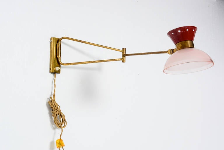 For your consideration a French wall sconce in the style Pierre Guariche. Articulated brass arm mounts into the wall. Pink glass shade with aluminum crown cover in red with traditional starts. 

Rewired, requires bayonet French bulb.

Unmarked, no