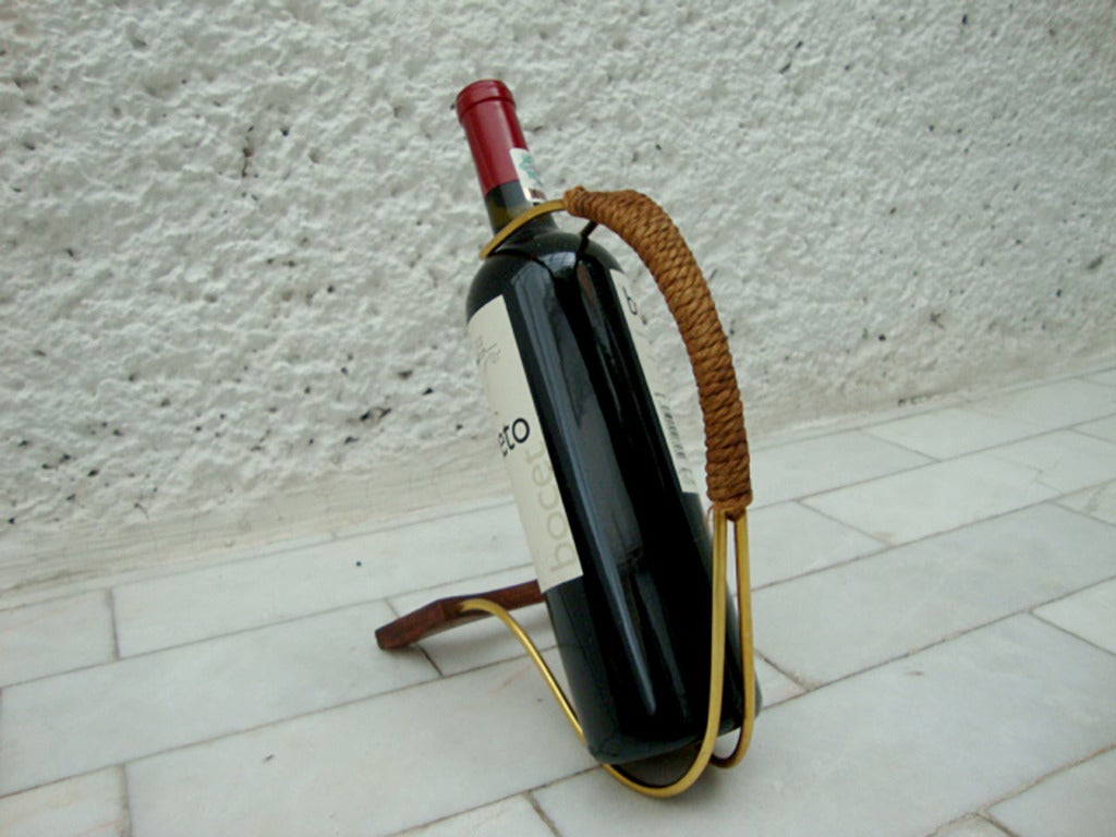 For your consideration a vintage wine holder with sculptural shape. 
Constructed with mahogany wood and brass frame. Handle is covered with rope. 

Unmarked.