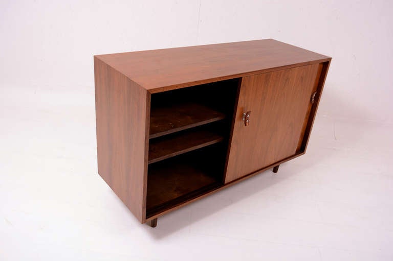For your consideration a vintage walnut cabinet or mini credenza designed by Milo Baughman for Glenn of California. 

Two sliding doors with sculptural handles with solid walnut wood and aluminum hardware. The left side is an open compartment for