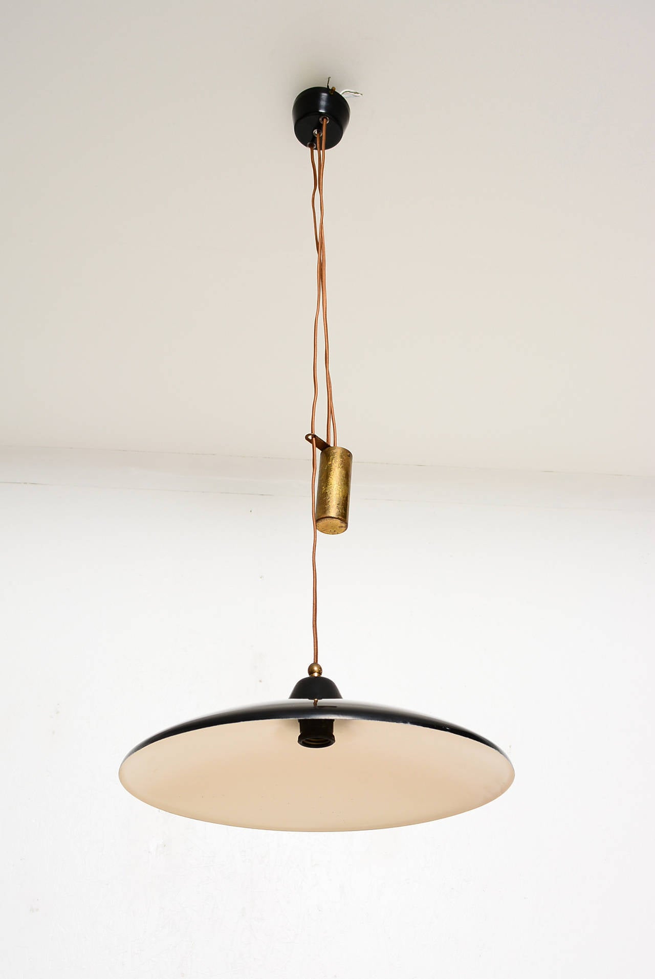 For your consideration an Italian hanging light fixture. 

Sculptural shape made of spun aluminum. Black satin finish with brass hardware. 

Heavy counterbalance weight helps to adjust the height of the light as desired. 

No bulb included.